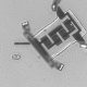 Microscopic image of a small electronic component with clear details of its structure and connections against a gray background.